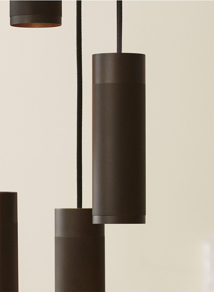 Nærbillede af loftlampe med fem pendler i massiv bruneret messing, diamant slebet mønster og sorte stof ledninger.