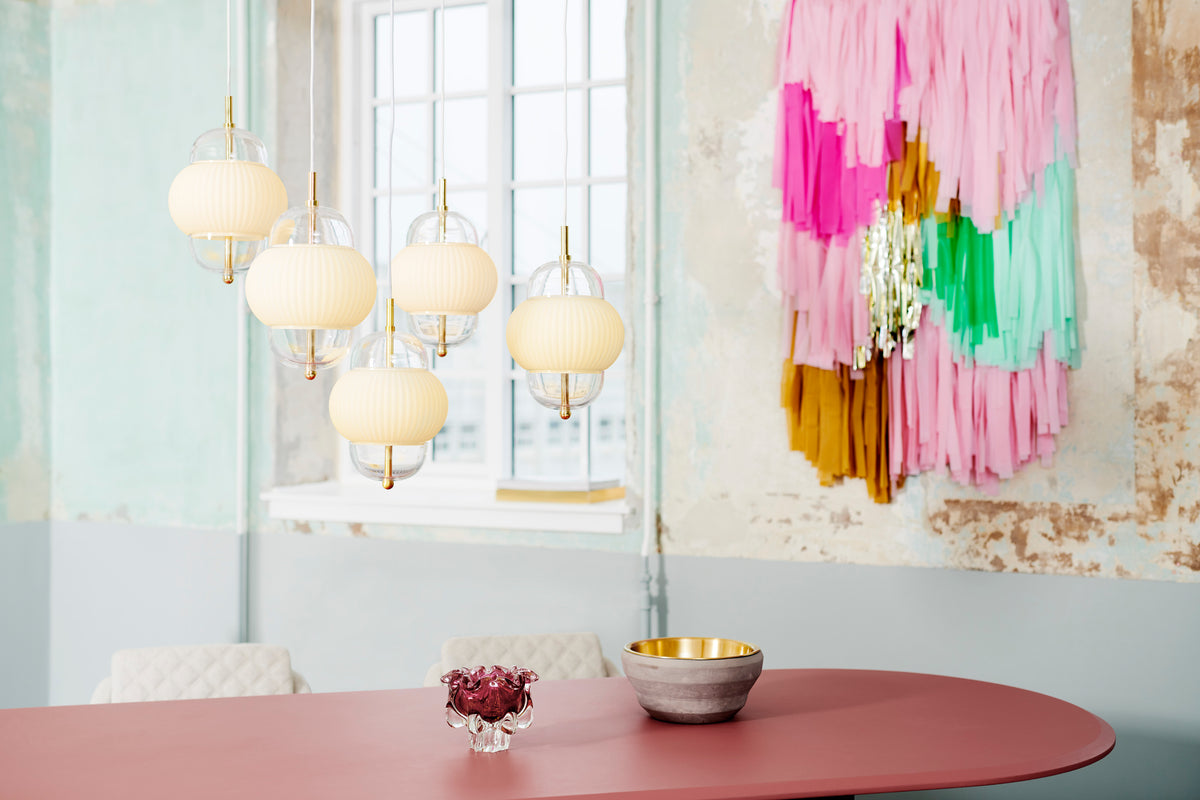 Lampe i klart glas og mat hvidt plisseret glas. Derudover har lampen detaljer i messing og en hvid stofledning. 