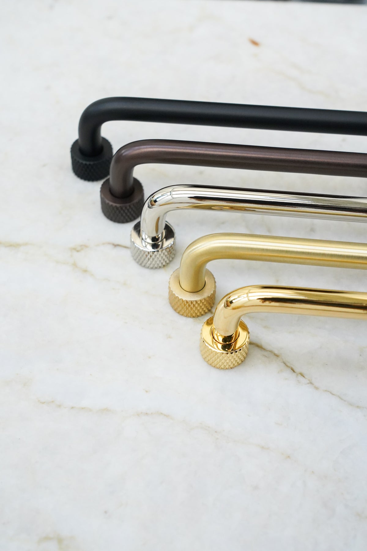 Køkkengreb i massiv messing med en mat sort overflade. Grebet har runde fødder med riflet diamond cut mønster, som matcher til quooker armatur.