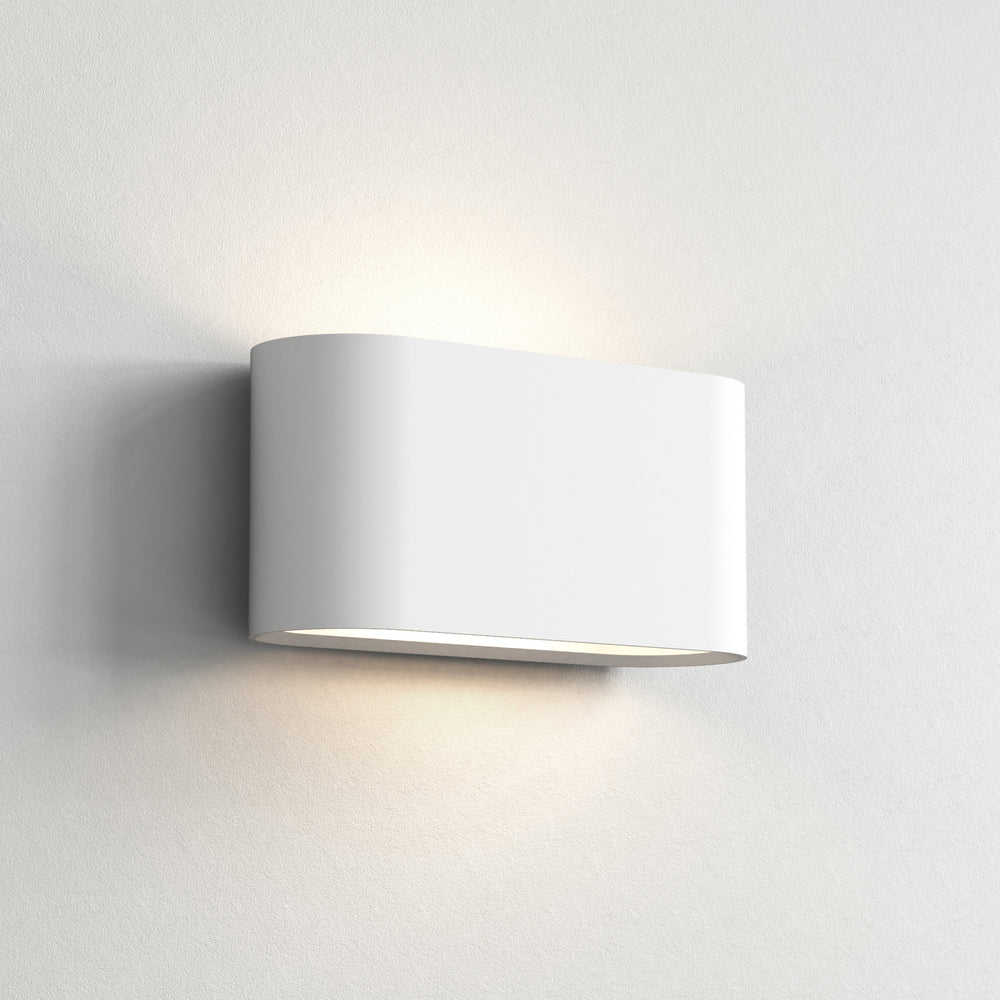 Aflang horisontal væglampe i hvid metal med bløde hjørner opadvendt og nedadvendt lys.