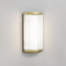 Lampe med top, bund og bagside i guldfarvet stål samt en glasskærm med nedadgående linjer.